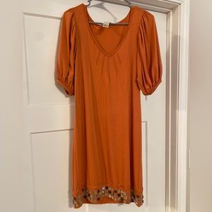 Orange Knee Length Dress with puff sleeves. Beaded detail along the bottom.